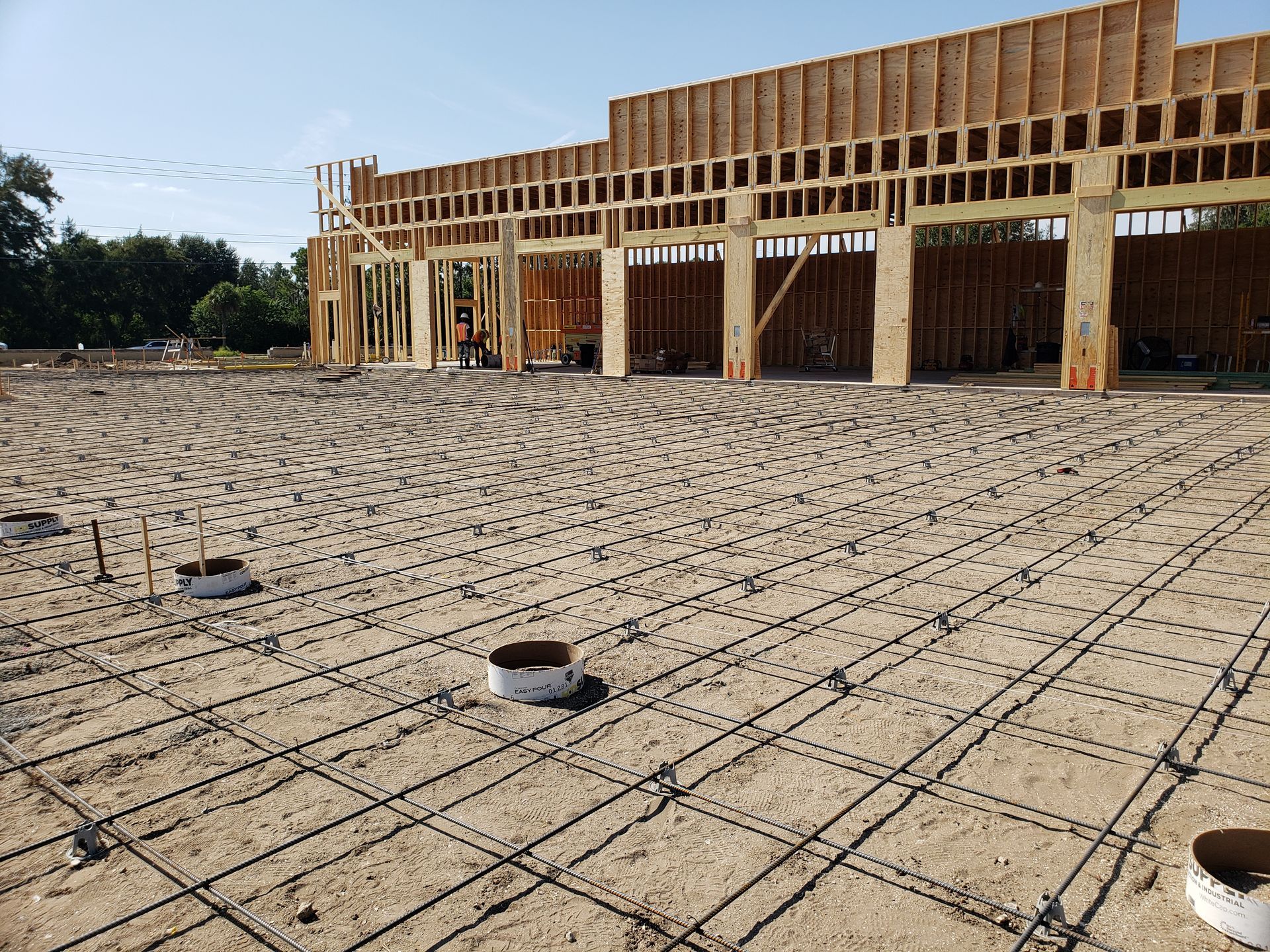 A large building is being built in the middle of a dirt field.