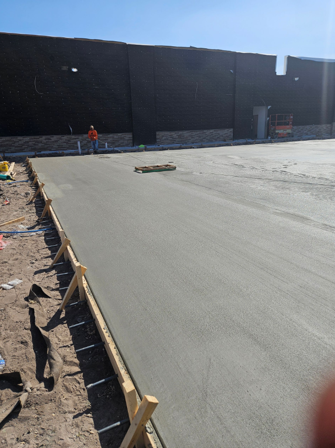 A concrete driveway is being built in front of a large building.