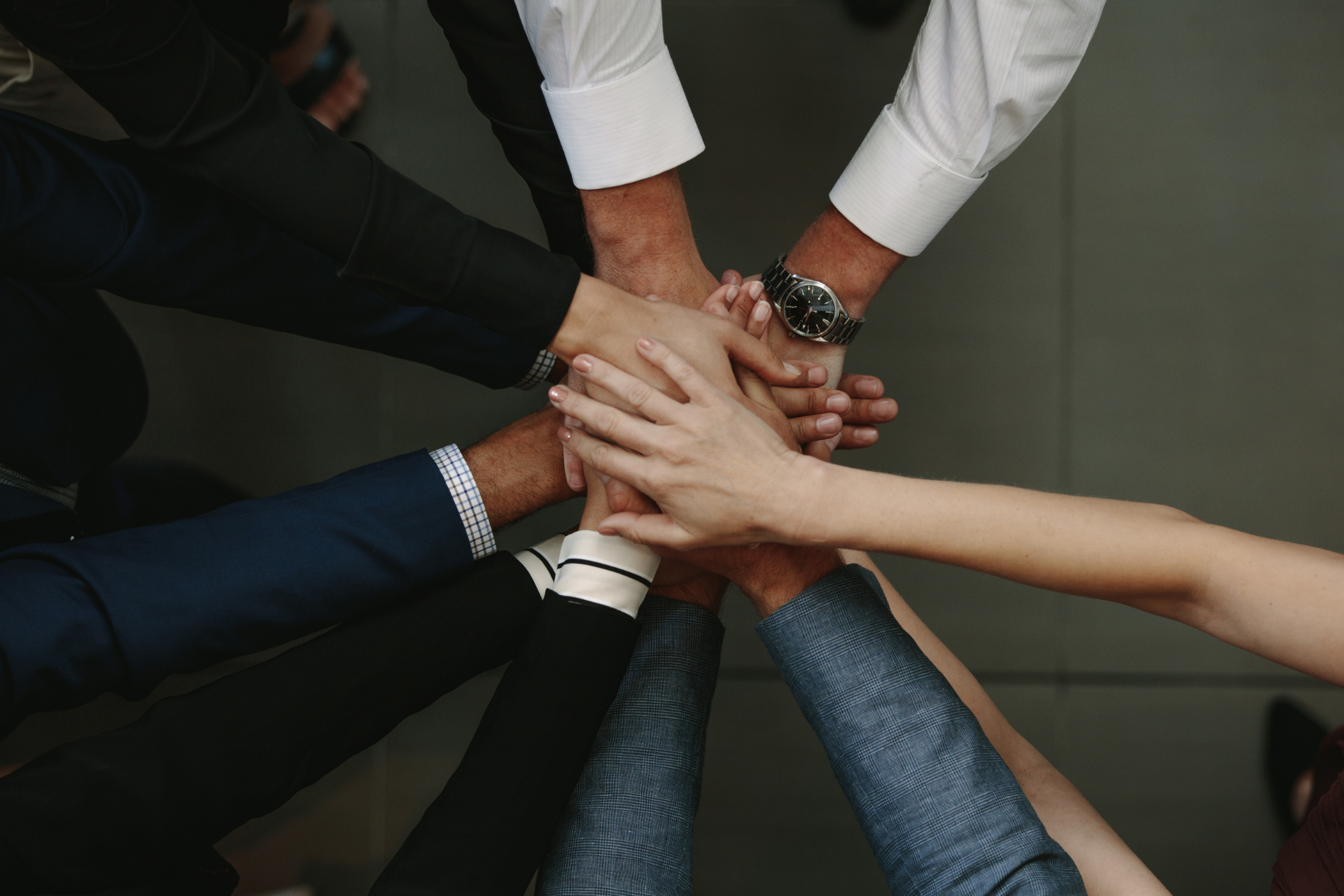Um grupo de pessoas está juntando as mãos em um círculo.