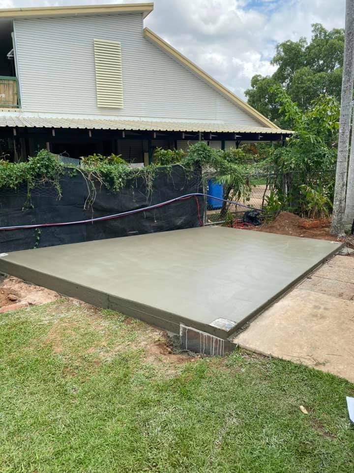 Newly poured concrete slab in a yard, next to a building and grass — Dwayne Hamlyn Concreting in Woodroffe, NT