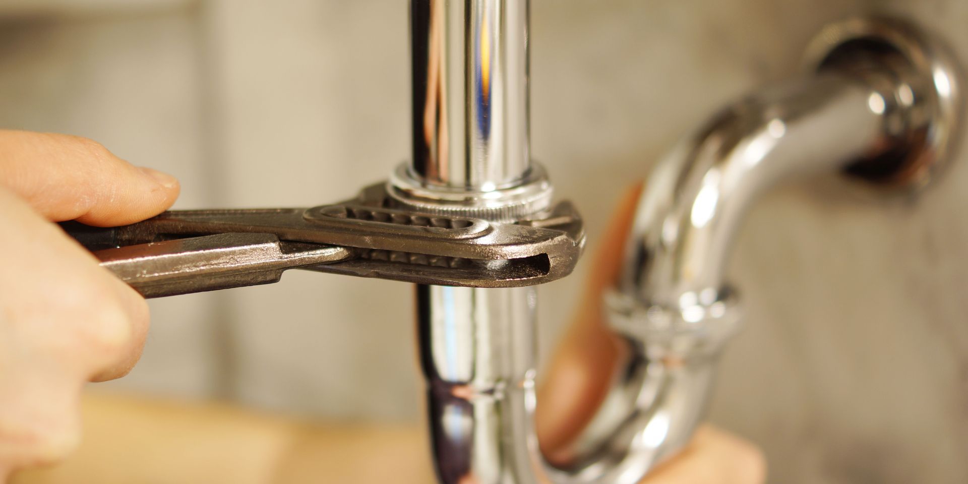 A person is fixing a pipe with a wrench.