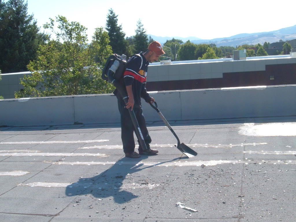 A man with a backpack is sweeping the ground with a broom