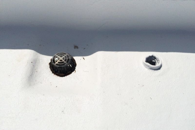 A close up of a drain on a white surface.