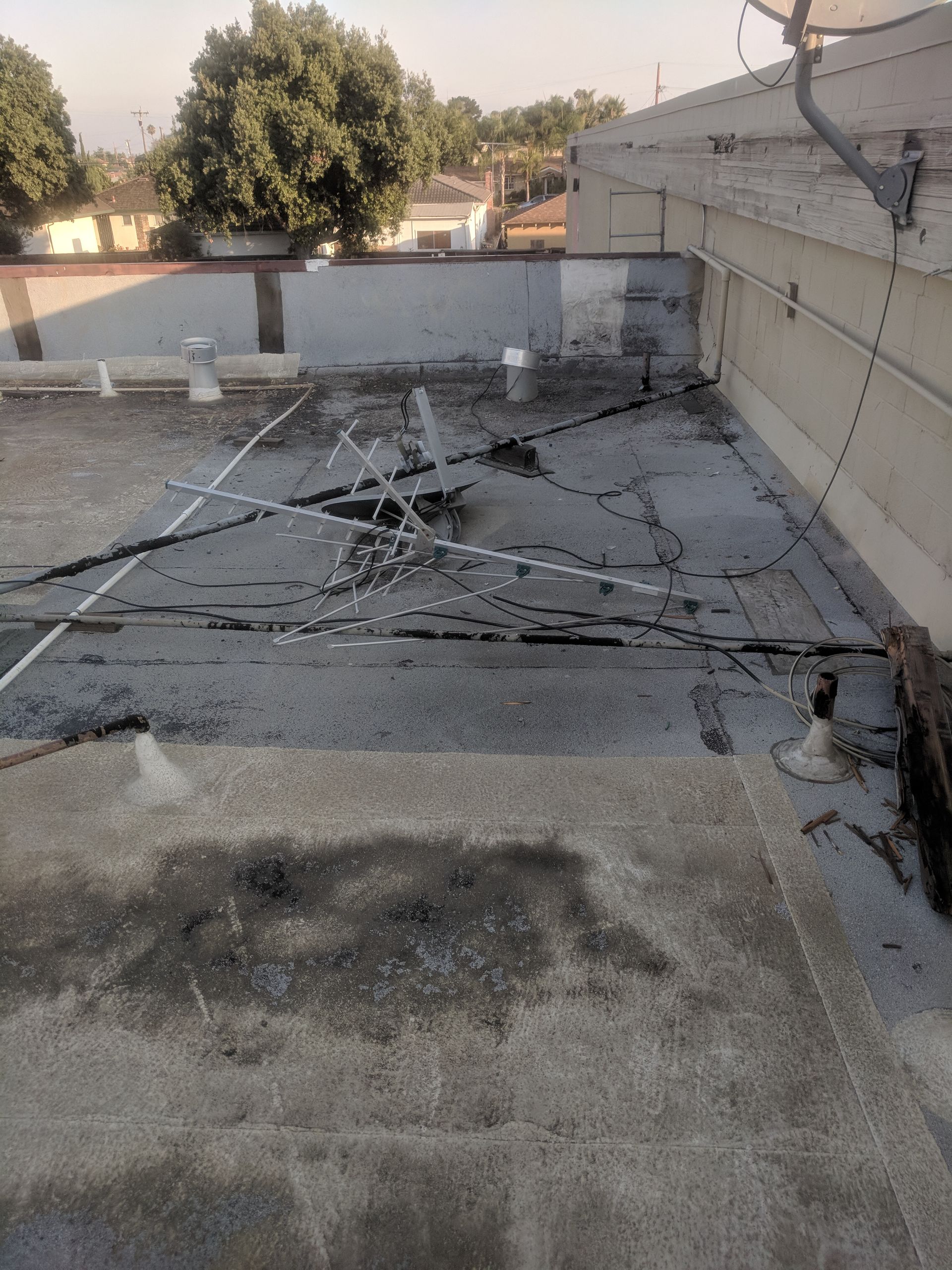 A roof with a lot of wires on it and a tree in the background.