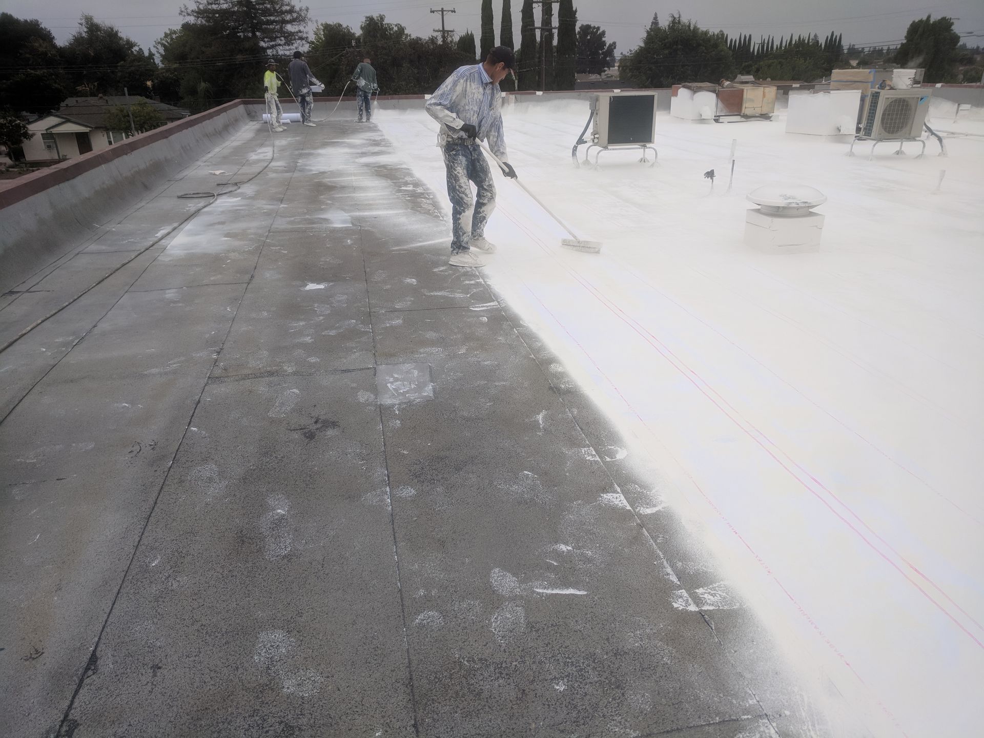 A man is painting a roof with a roller.