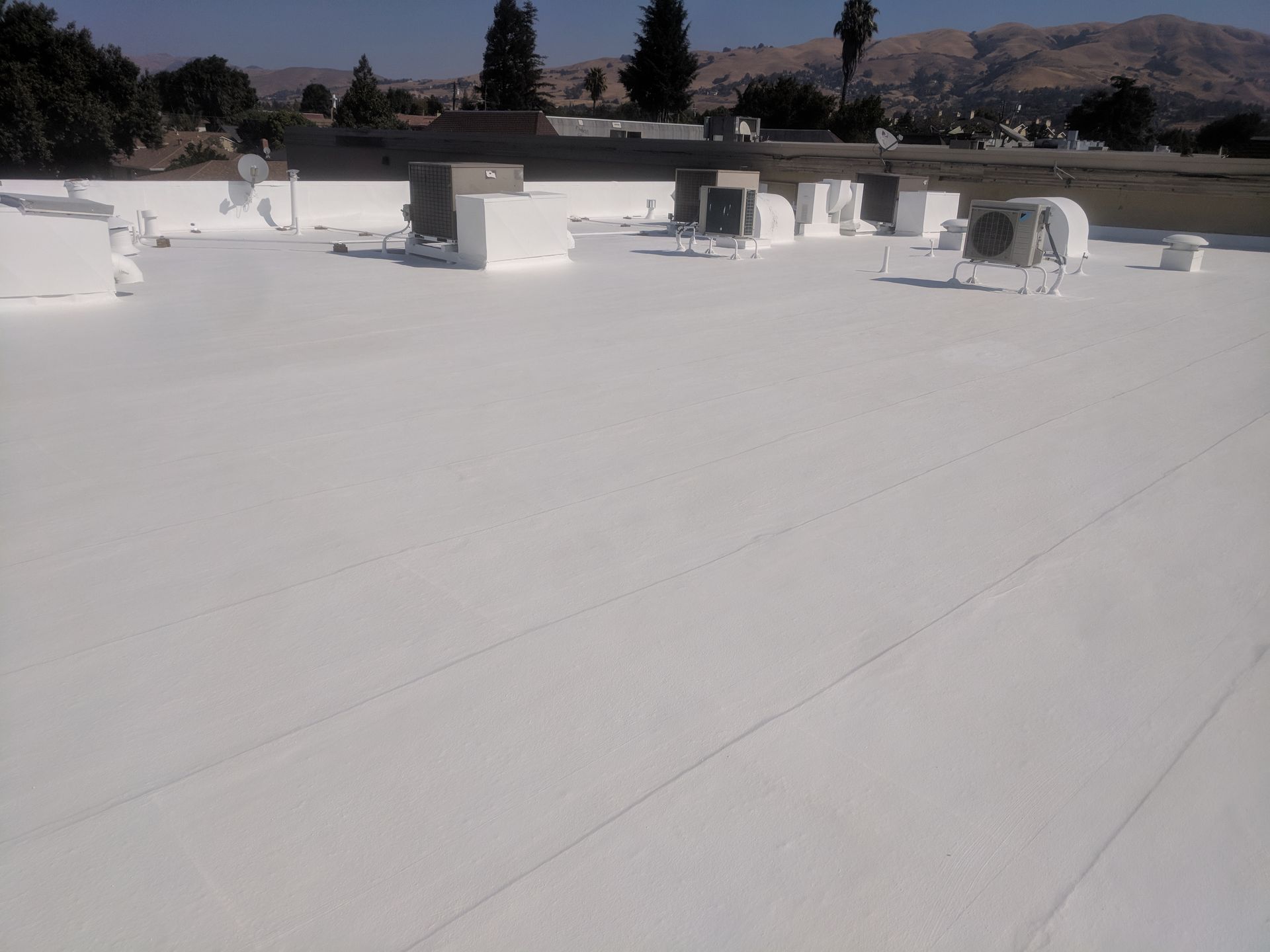 A white roof with a lot of air conditioners on it