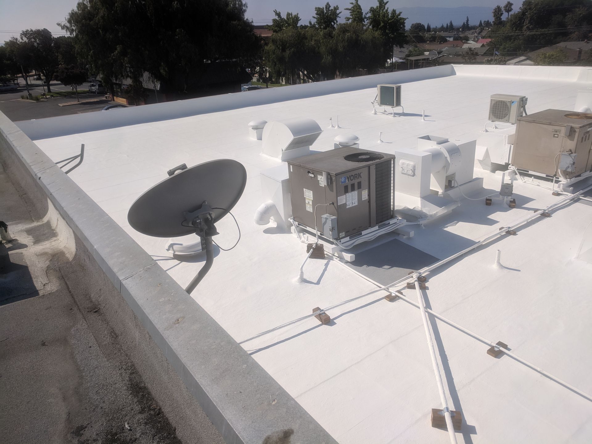A satellite dish sits on top of a white roof