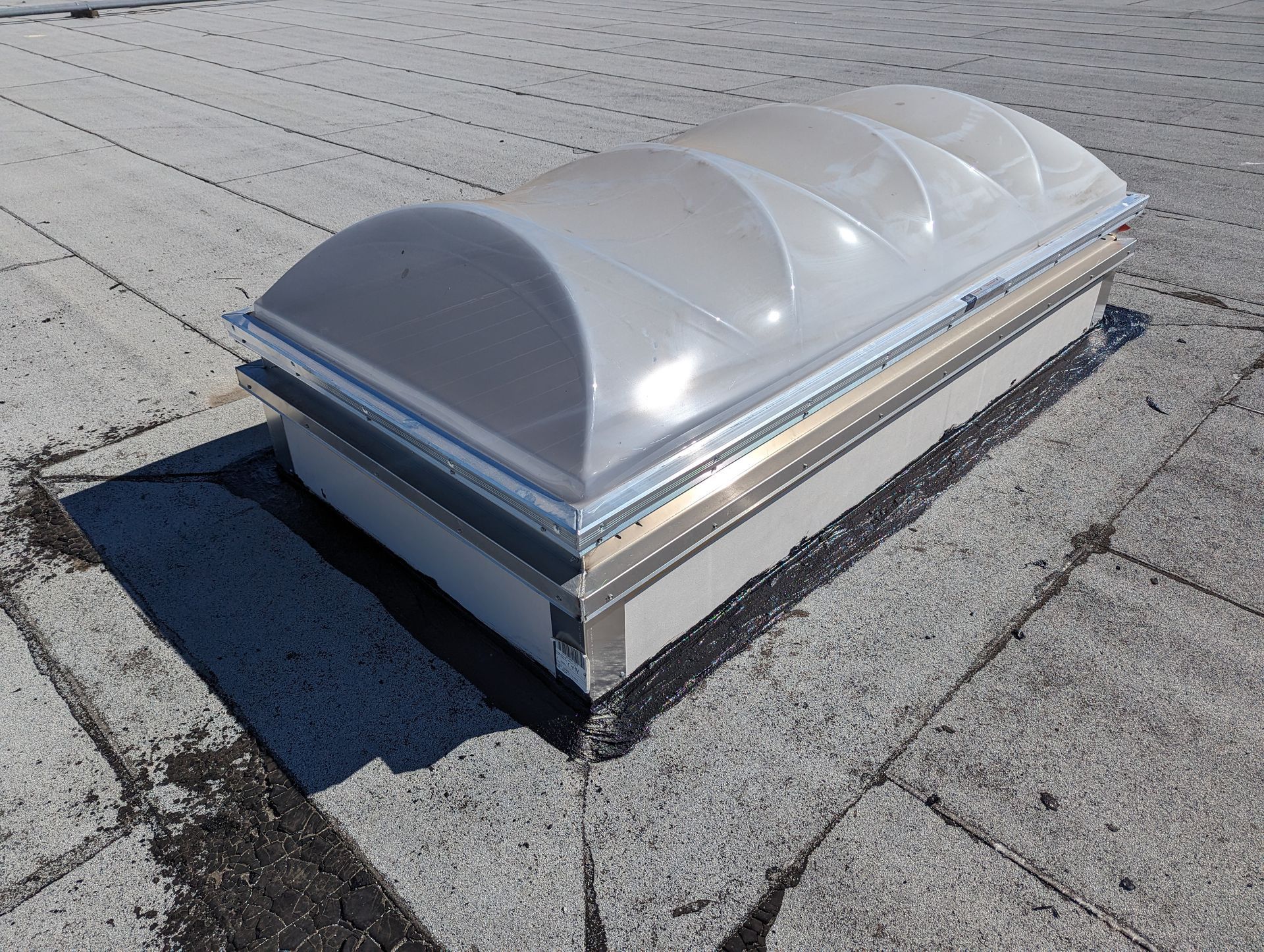 A dome shaped skylight is sitting on top of a brick roof