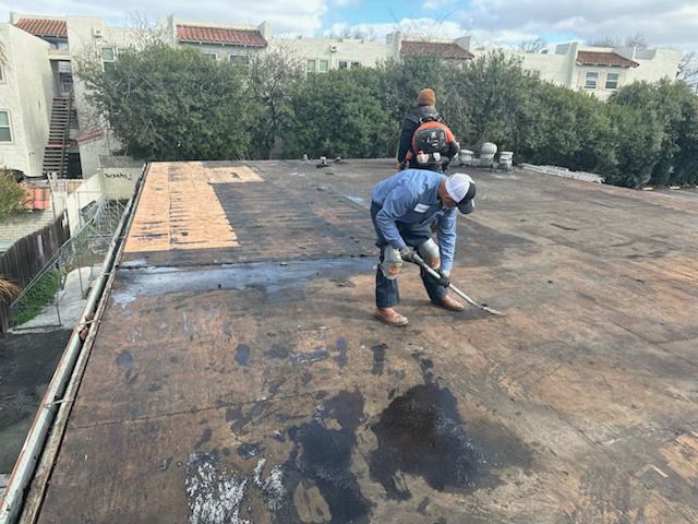 A man with a backpack is sweeping the ground with a broom