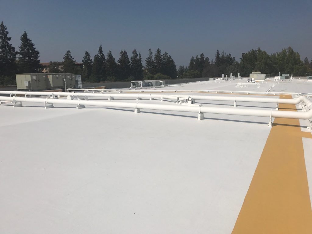 The roof of a building has been painted white and has a yellow stripe on it.