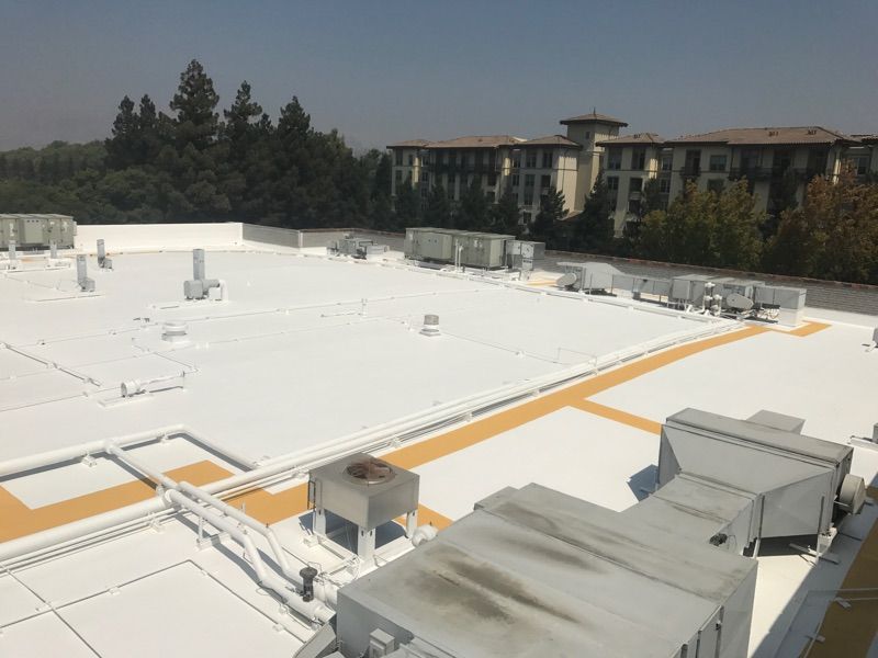 The roof of a building with a white roof and trees in the background.
