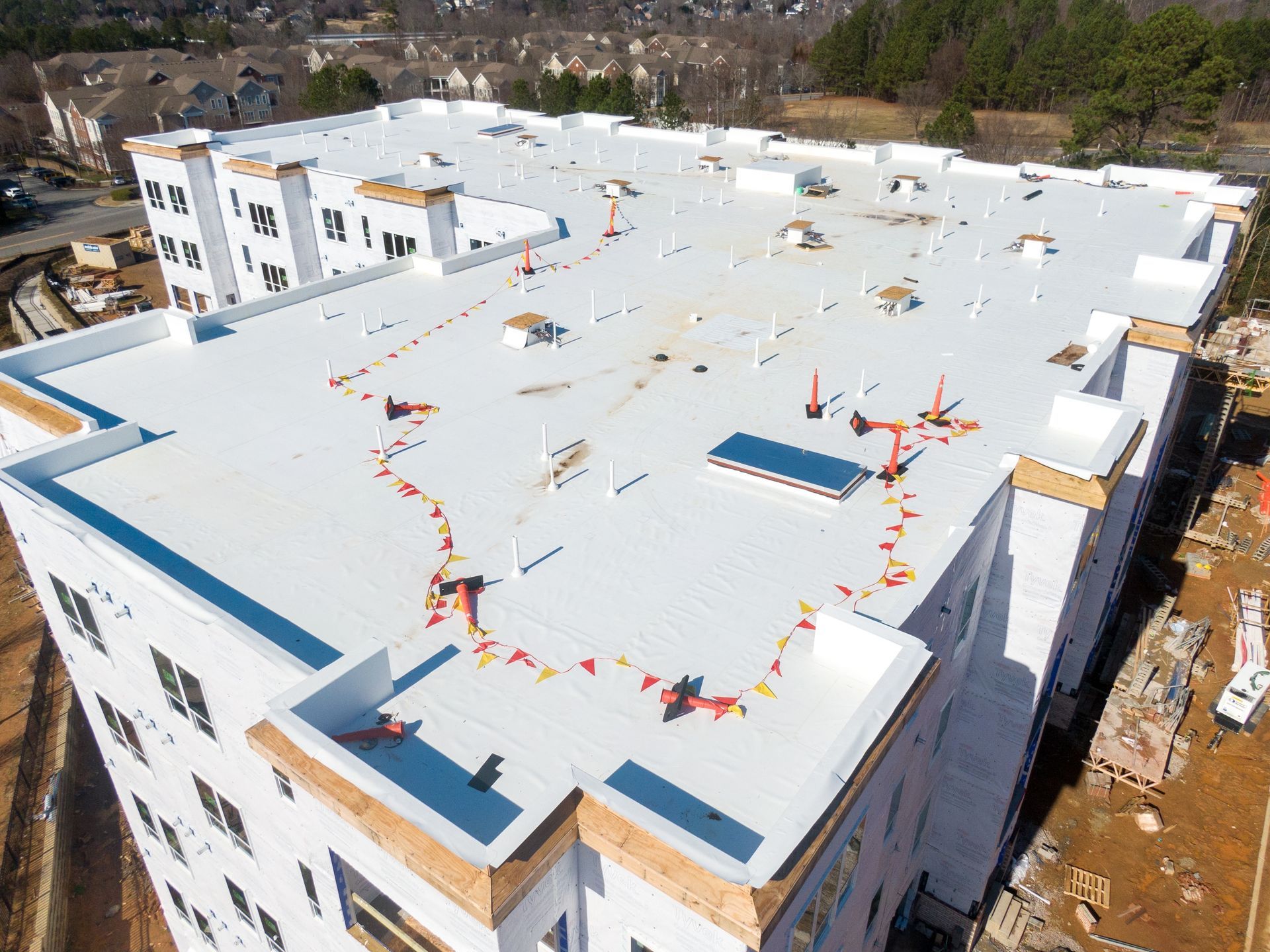 An aerial view of a building under construction with a white roof.