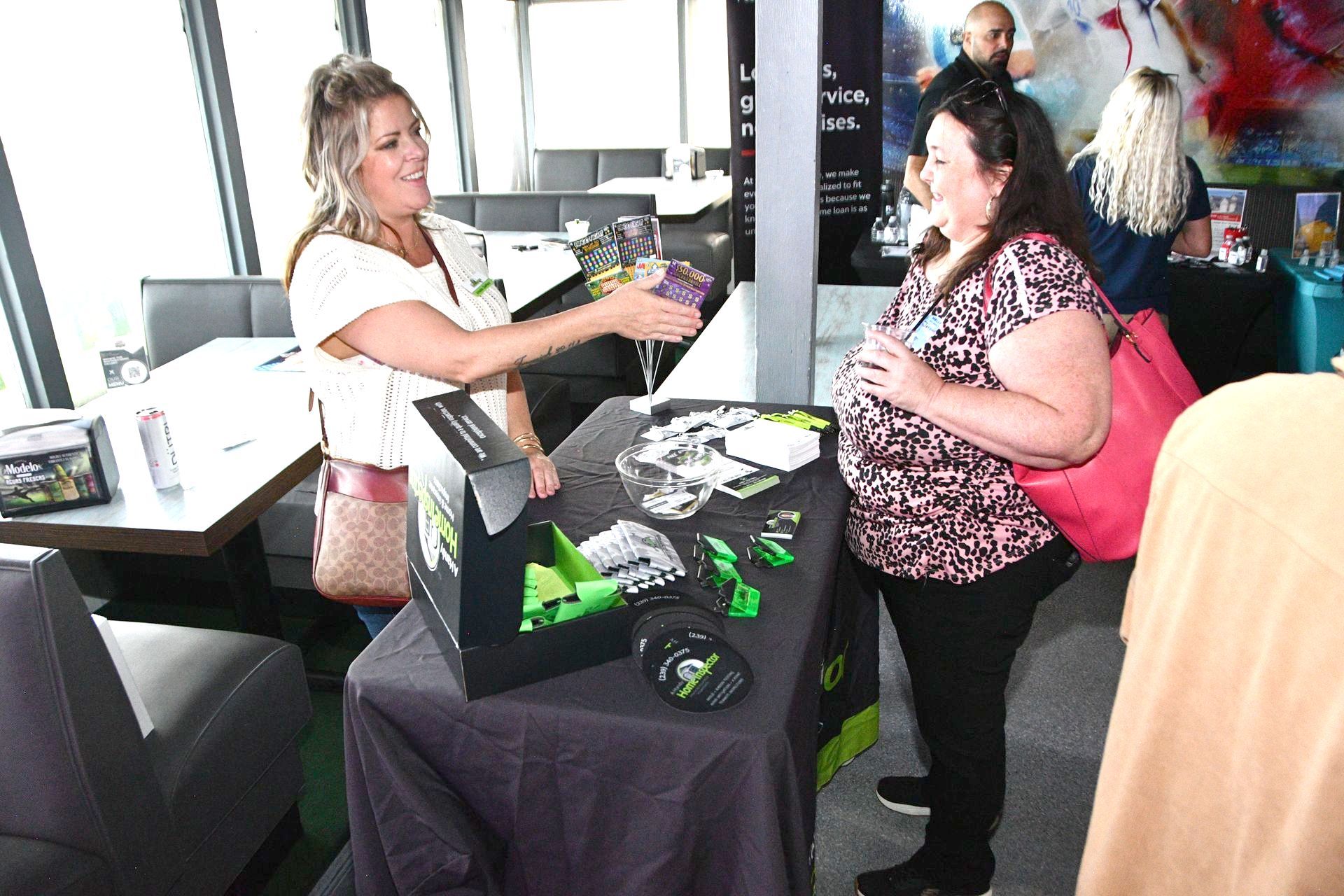 A woman is giving a gift to another woman at a table.