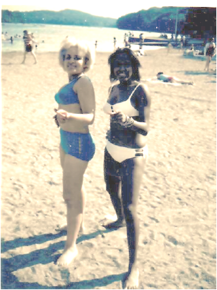 Two women in bikinis are standing on a sandy beach