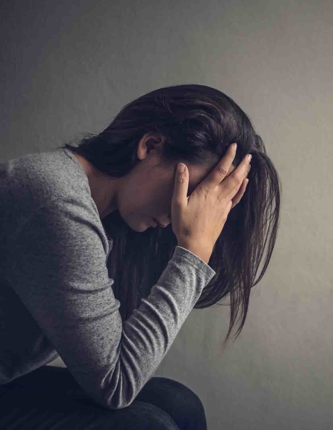 Mental Health — Depressed Woman Sitting on a Chair in Dark Room in Topeka, KS