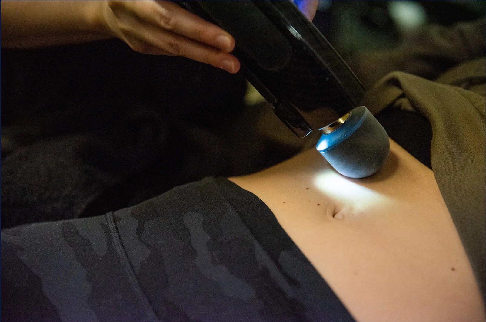 A woman is laying in a bed with a machine spraying ice on her face.