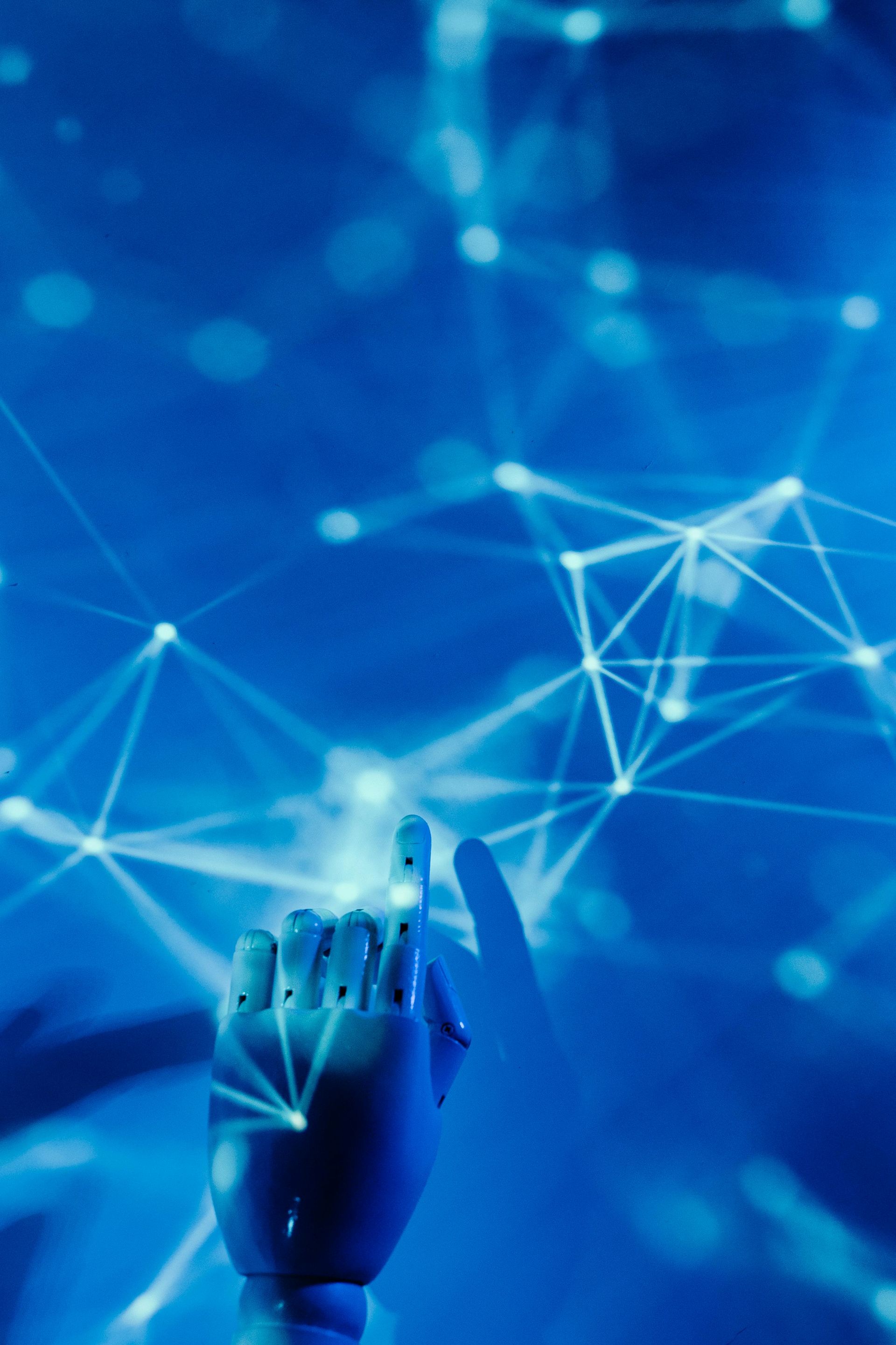 Robotic hand reaching towards a glowing network of connected nodes, all against a blue backdrop.