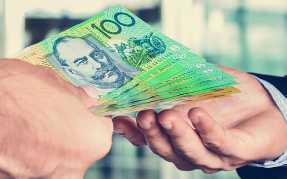 Hands exchanging Australian $100 banknotes, representing payment or transaction.