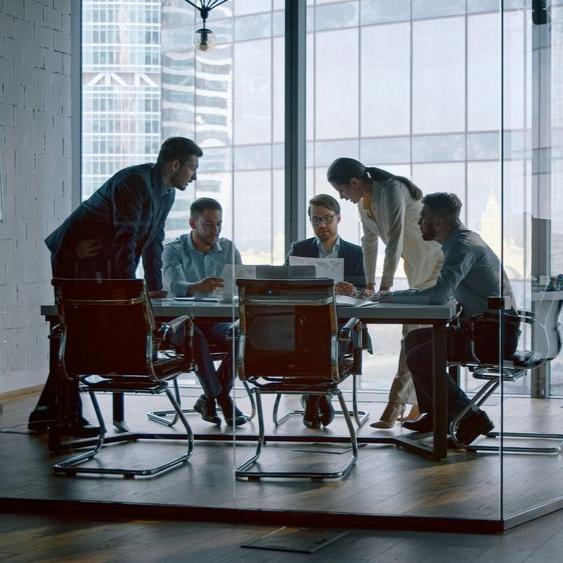 Business team meeting around a conference table in an office setting.