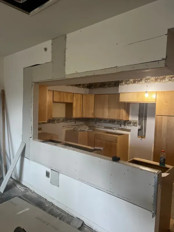 A kitchen under construction with a window in the wall.