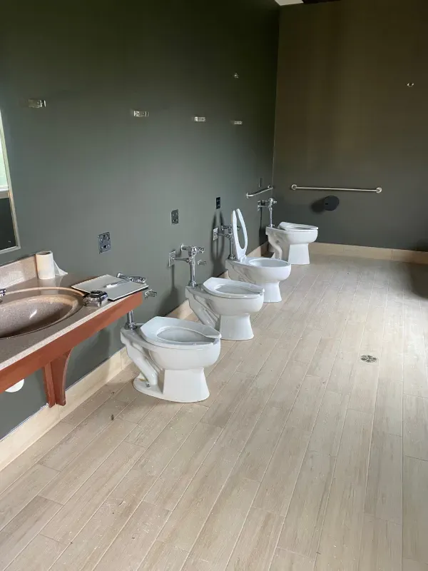 A bathroom with a row of toilets and a sink.