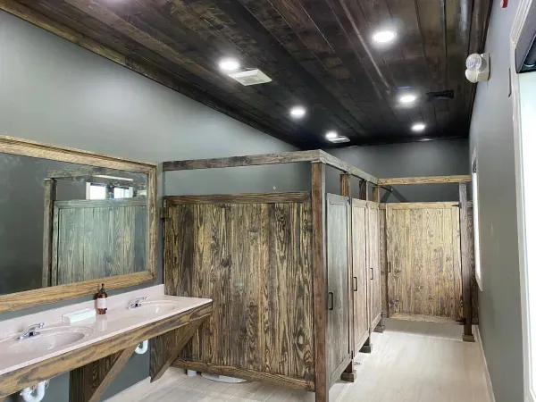 A bathroom with wooden stalls , sinks and mirrors.