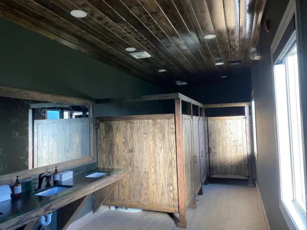 A bathroom with wooden stalls and a sink.