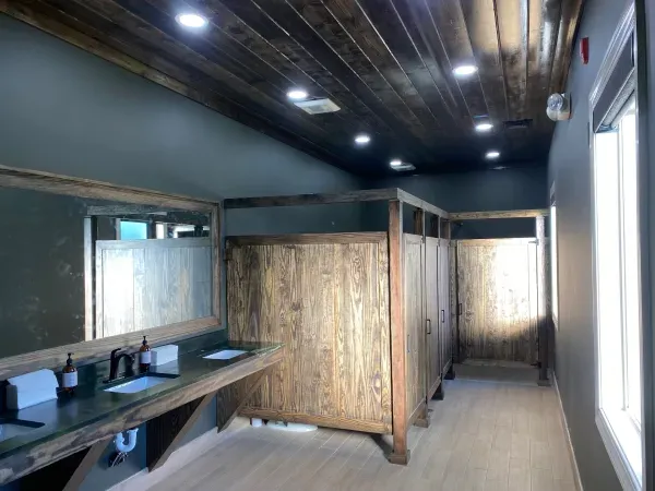 A bathroom with wooden stalls , sinks and mirrors.