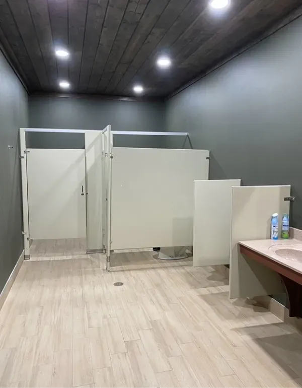 A bathroom with three stalls and a sink