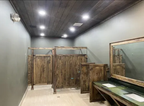 A bathroom with wooden stalls and a mirror