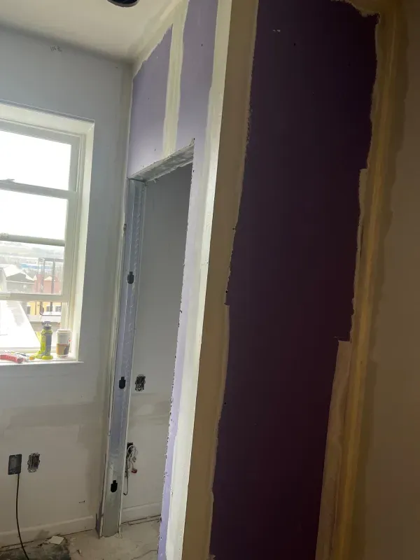 A room with a purple wall and a window.