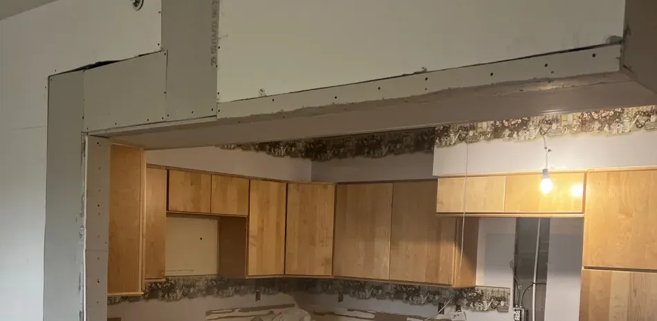 A kitchen with wooden cabinets and a white wall.