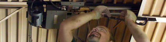 Garage Door Installations — Man Repairing Garage Door in Lomita, CA