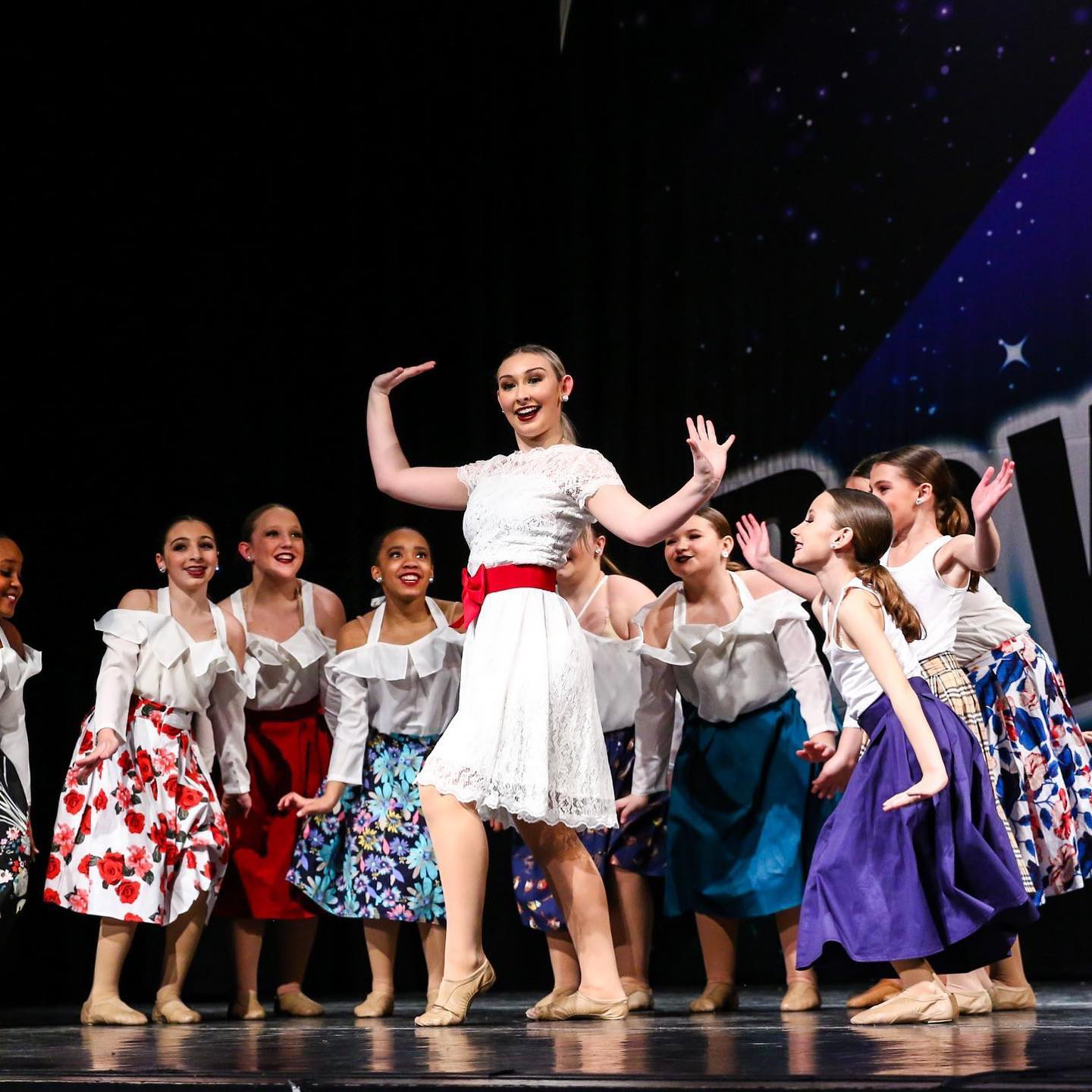 A group of young girls are dancing on a stage.