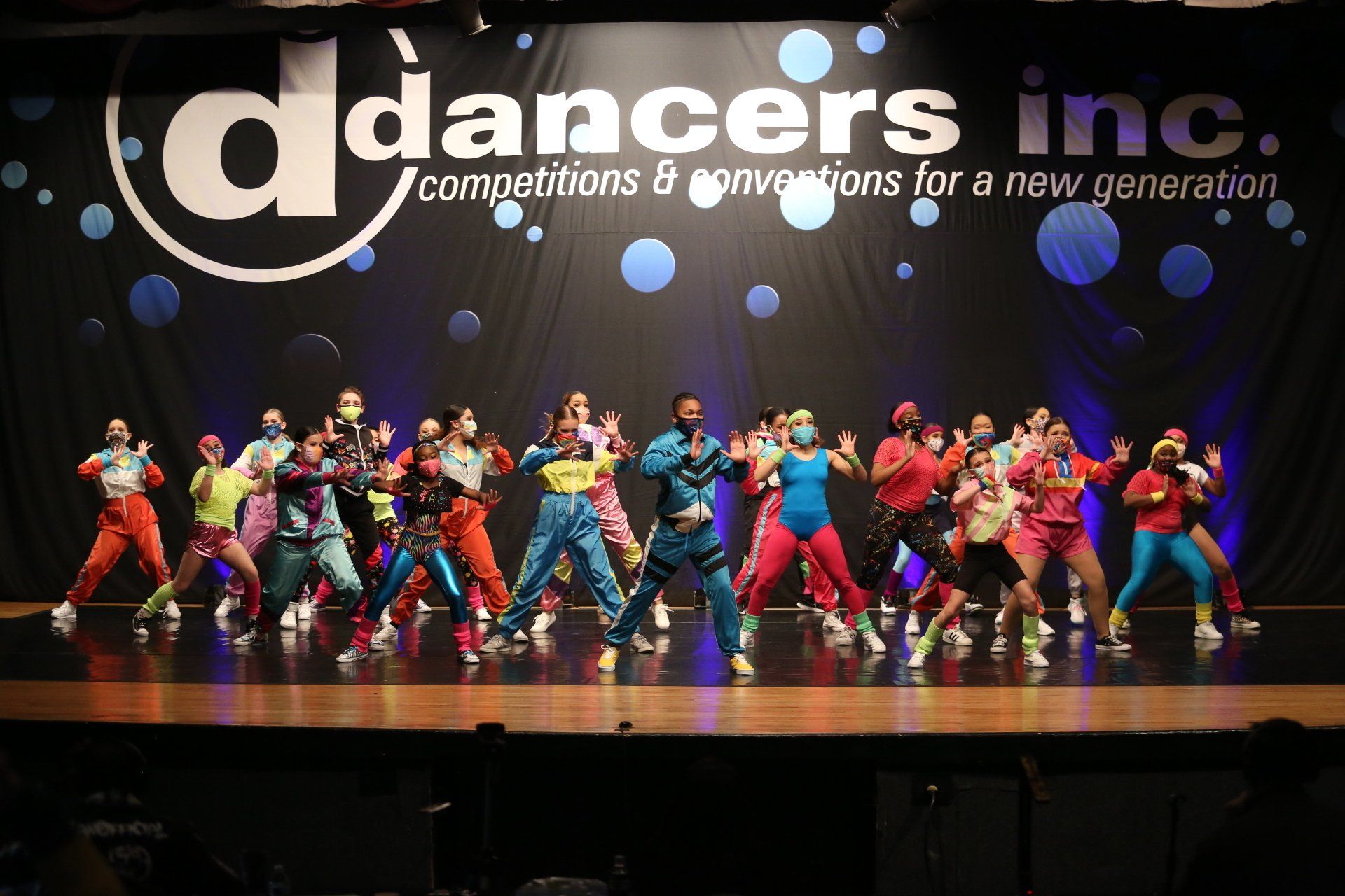 A group of dancers are performing on a stage in front of a sign that says dancers inc.