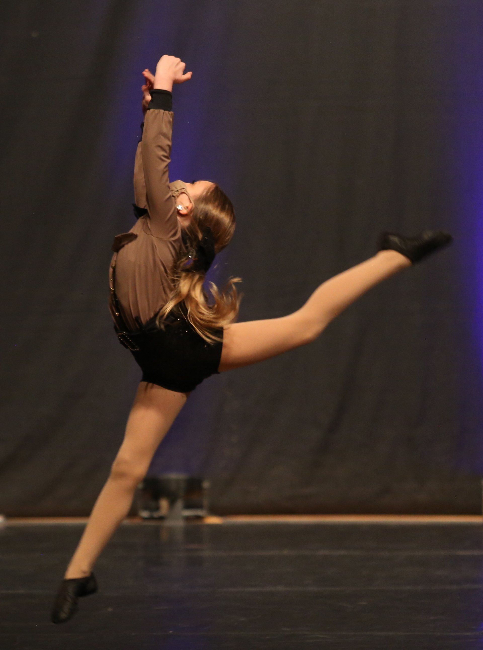 A young girl is doing a split on a dance floor