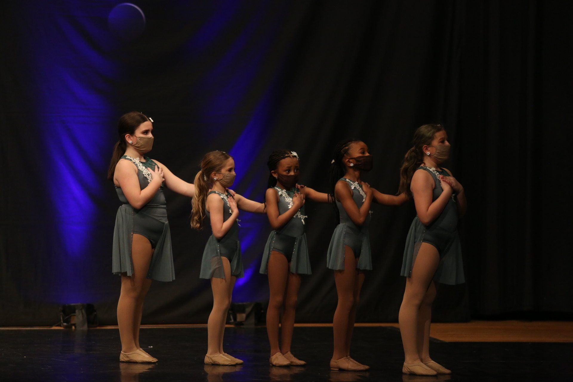 A group of young girls are standing next to each other on a stage.