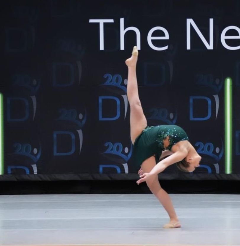 A woman is doing a handstand in front of a sign that says the new