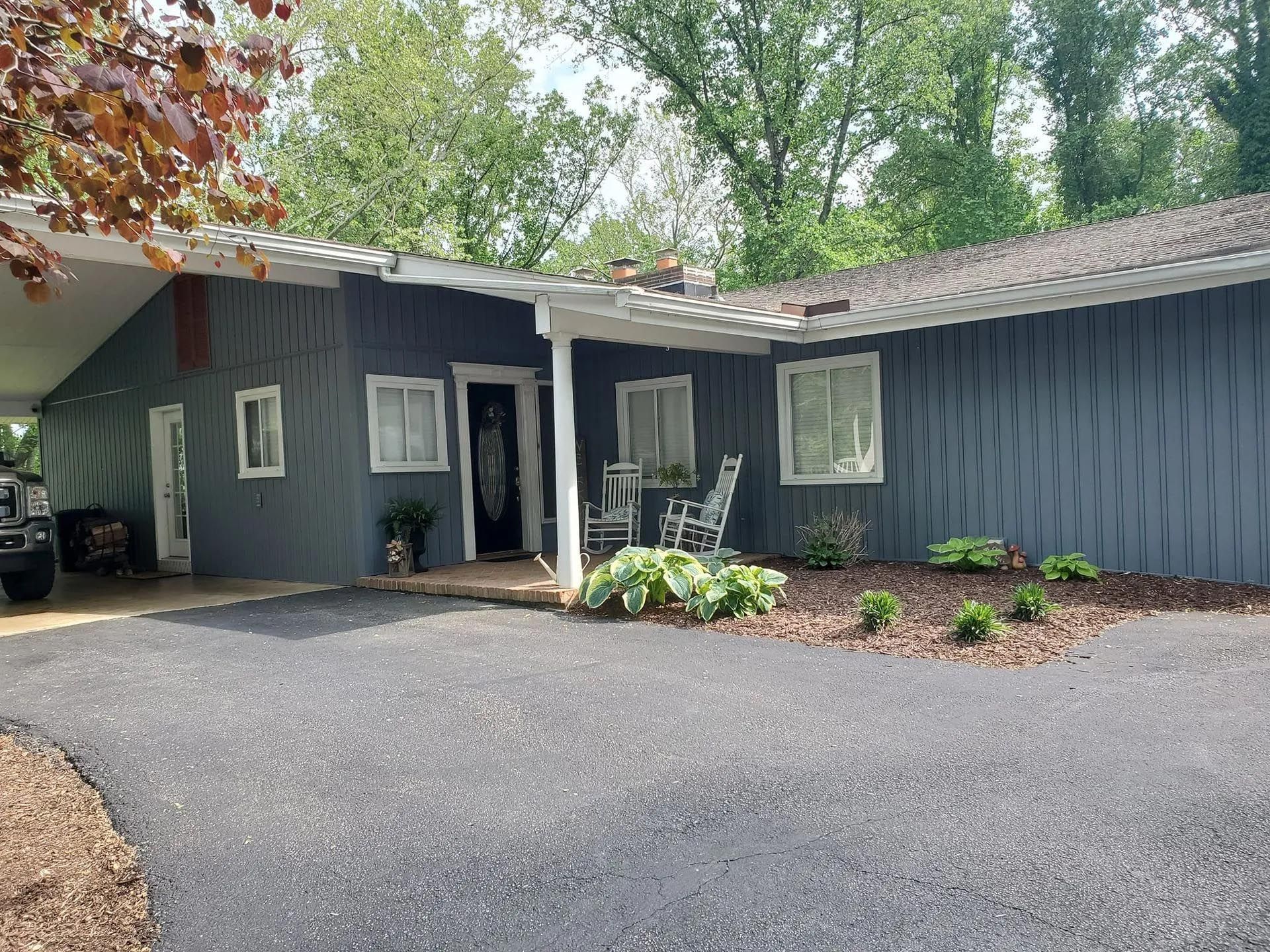 A blue house with a porch and a truck parked in front of it.