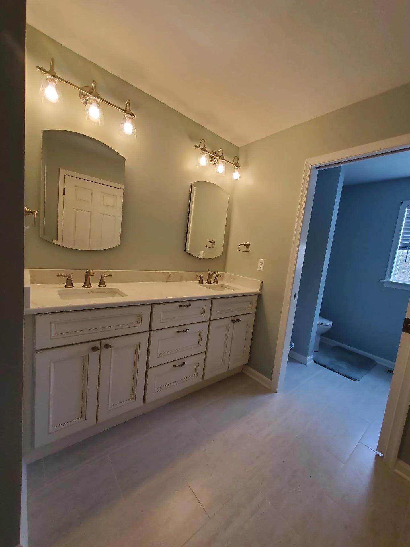 A bathroom with two sinks , a mirror and a toilet.