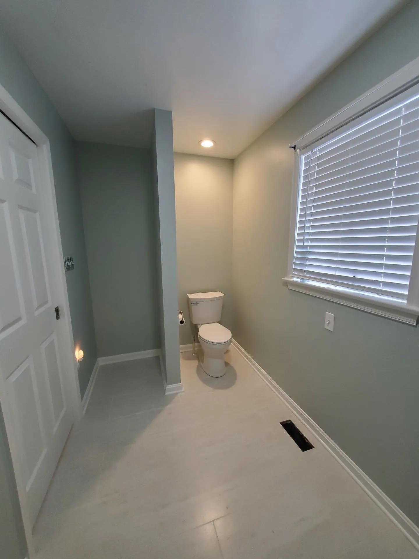 A bathroom with a toilet and a window.