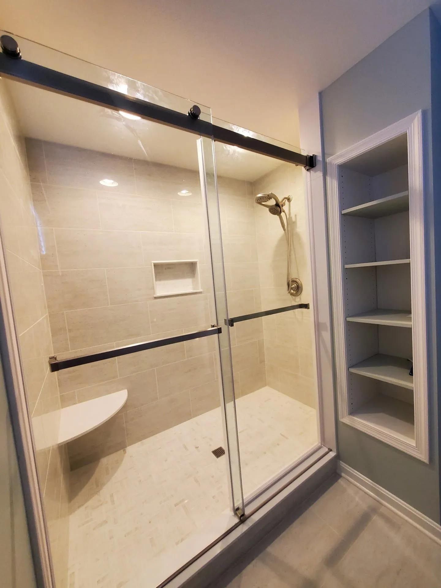 A bathroom with a sliding glass shower door and a bench.