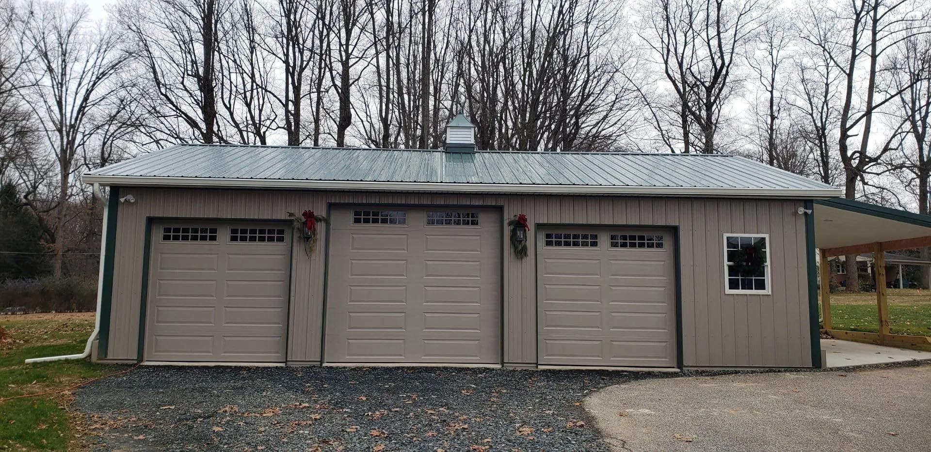 A garage with three garage doors and a green roof.