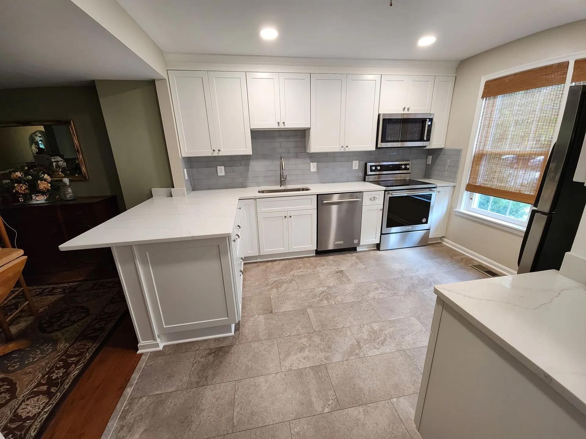 A kitchen with white cabinets , stainless steel appliances , and a large island.