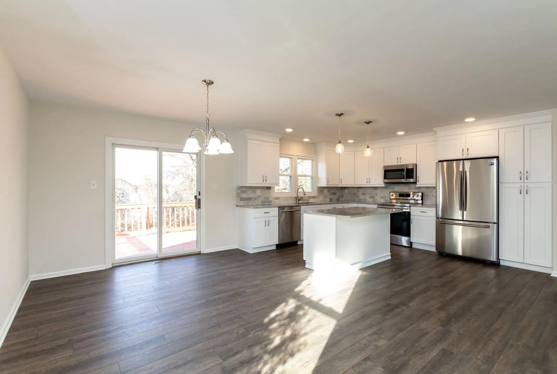 An empty kitchen with white cabinets and stainless steel appliances.