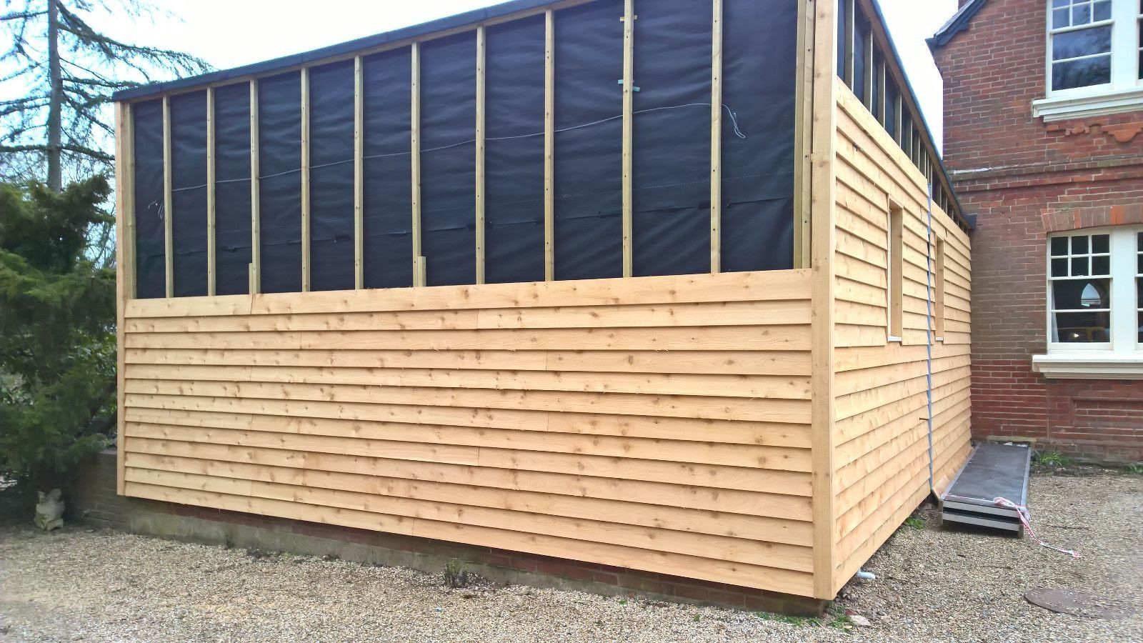A wooden building is being built next to a brick building.