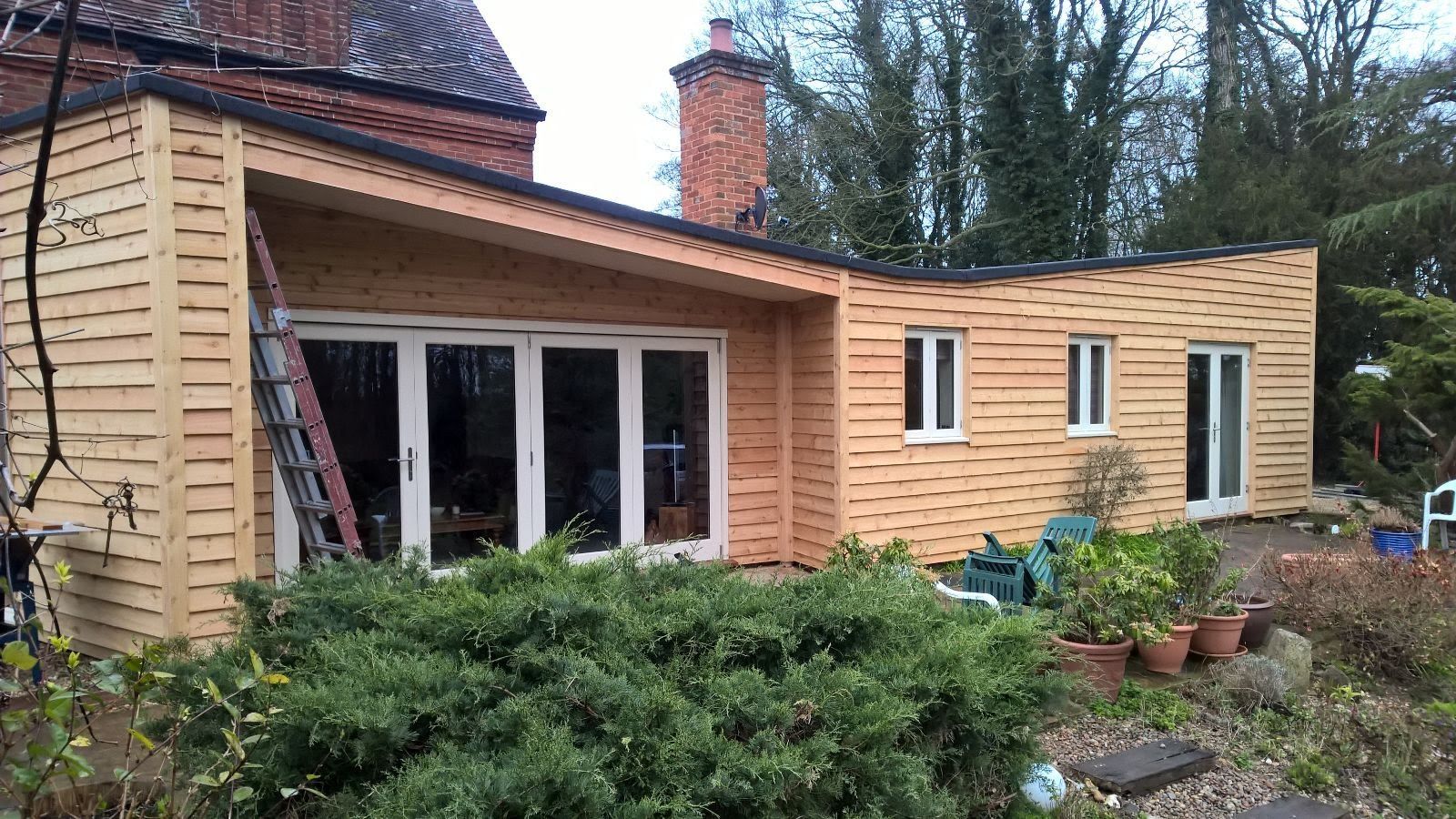 A wooden house with a lot of windows and a ladder in front of it.