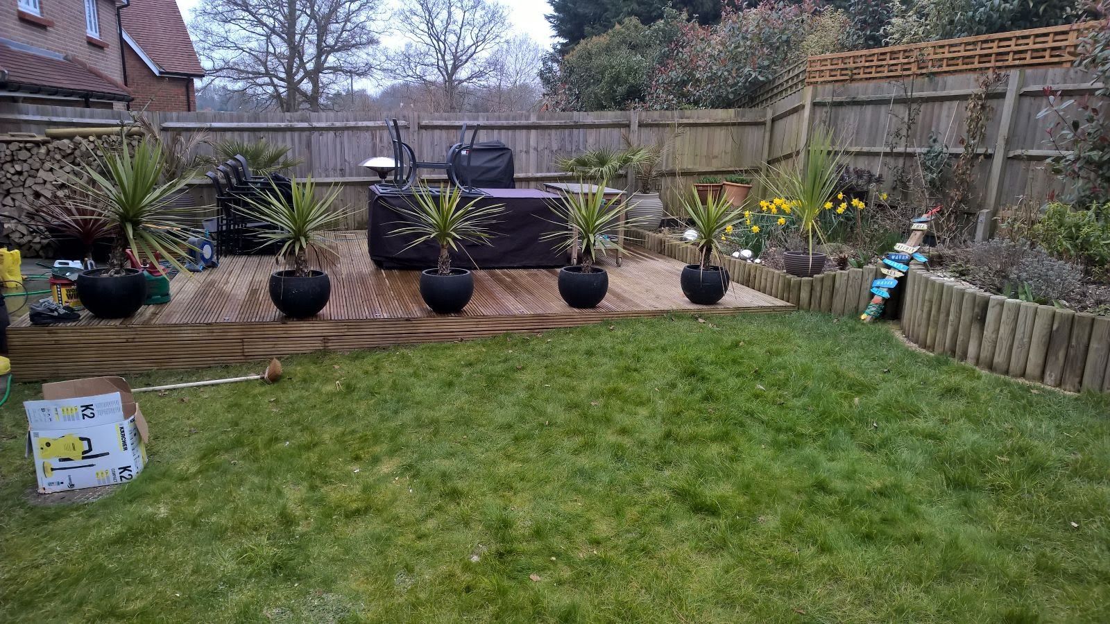 A backyard with a wooden deck and potted plants.