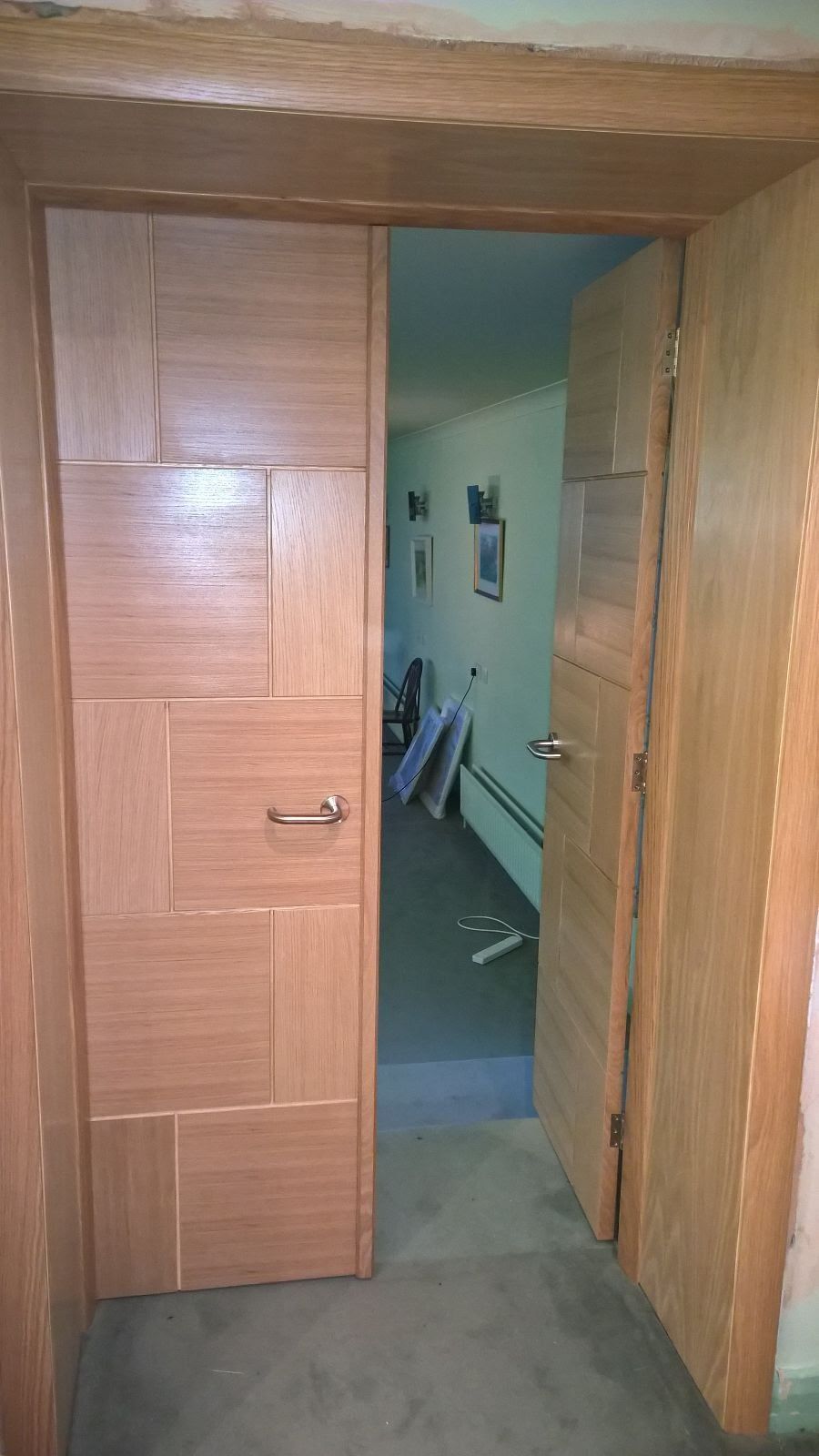 A wooden door is open in a hallway leading to a room.