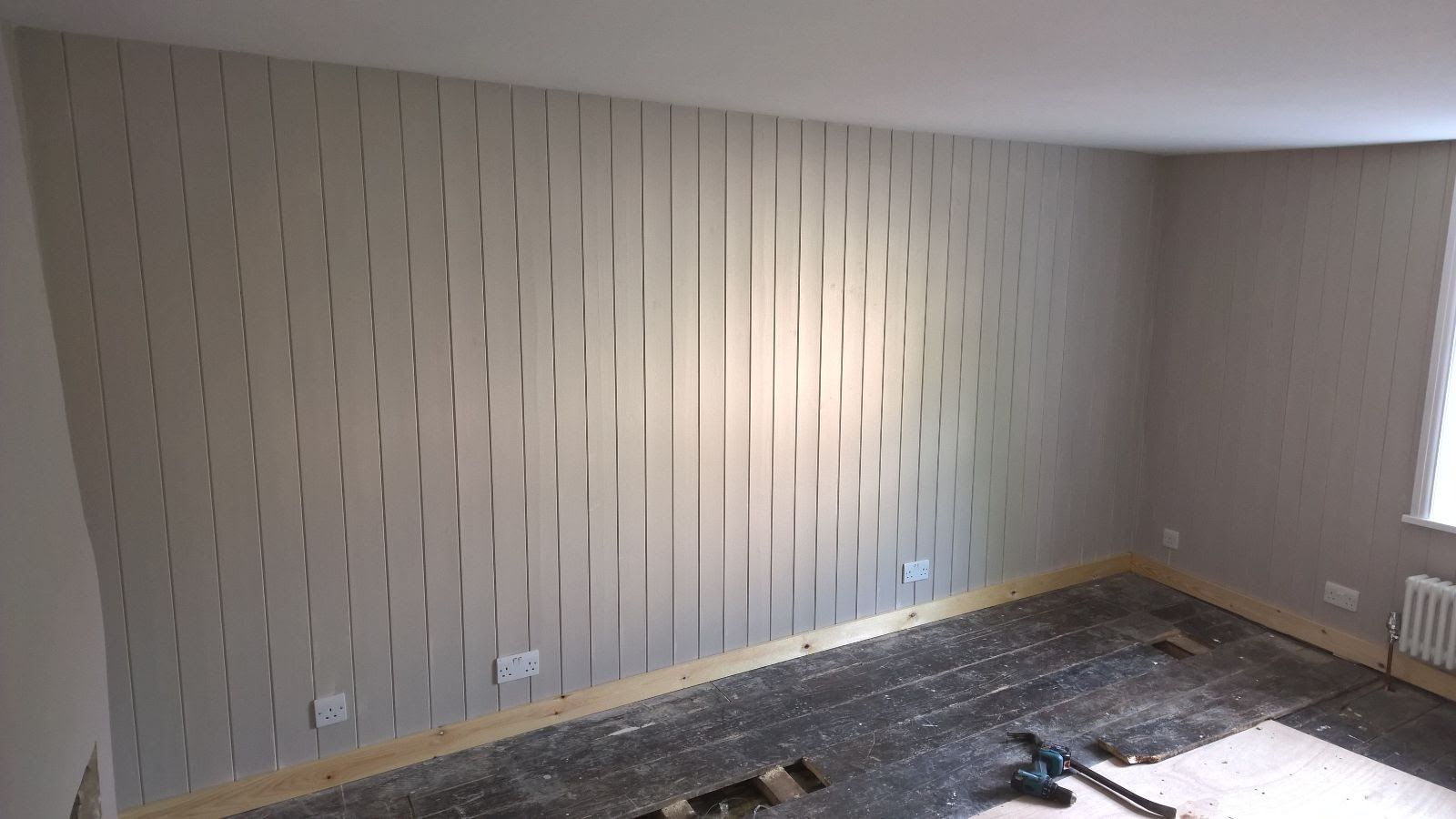 A room with a striped wallpaper on the wall and a vacuum cleaner on the floor.